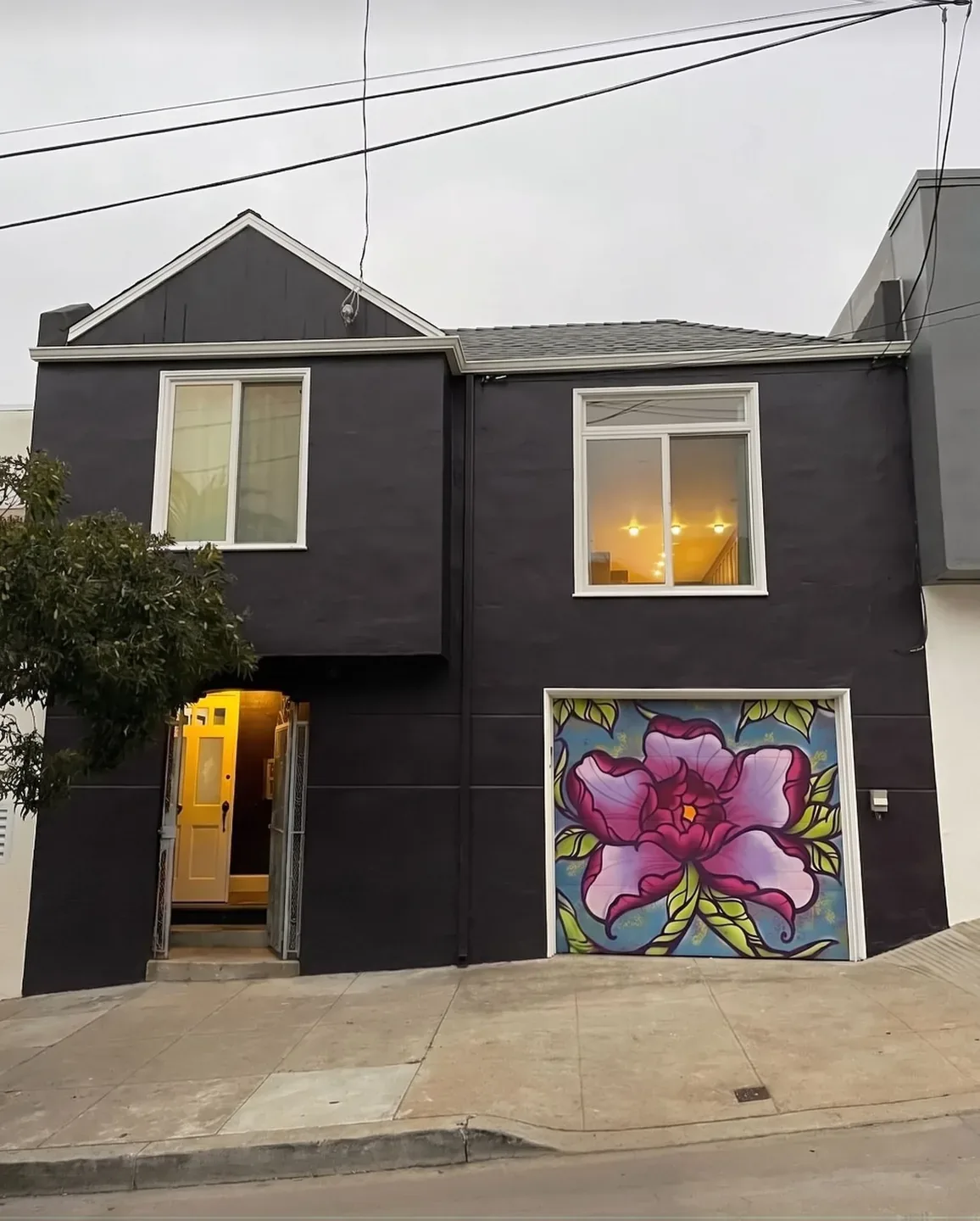 Two-storey house repainted charcoal with white trim; the flower mural on the garage door was kept