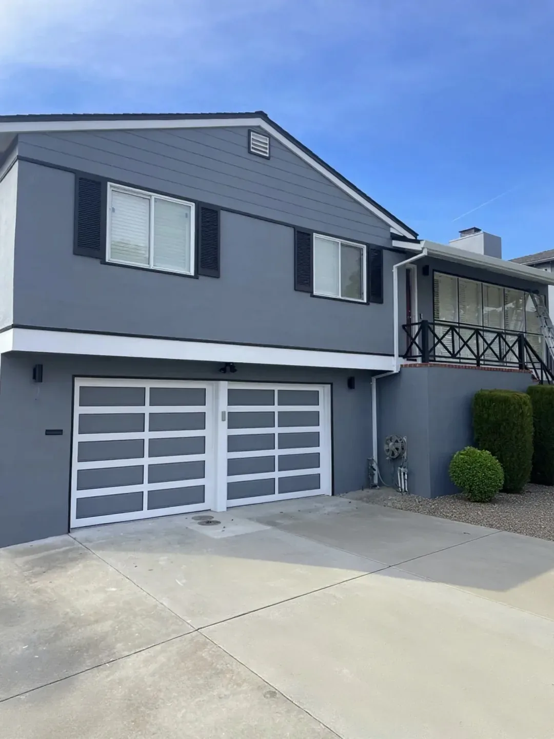 Two-storey house repainted grey with white trim and a white panelled garage door