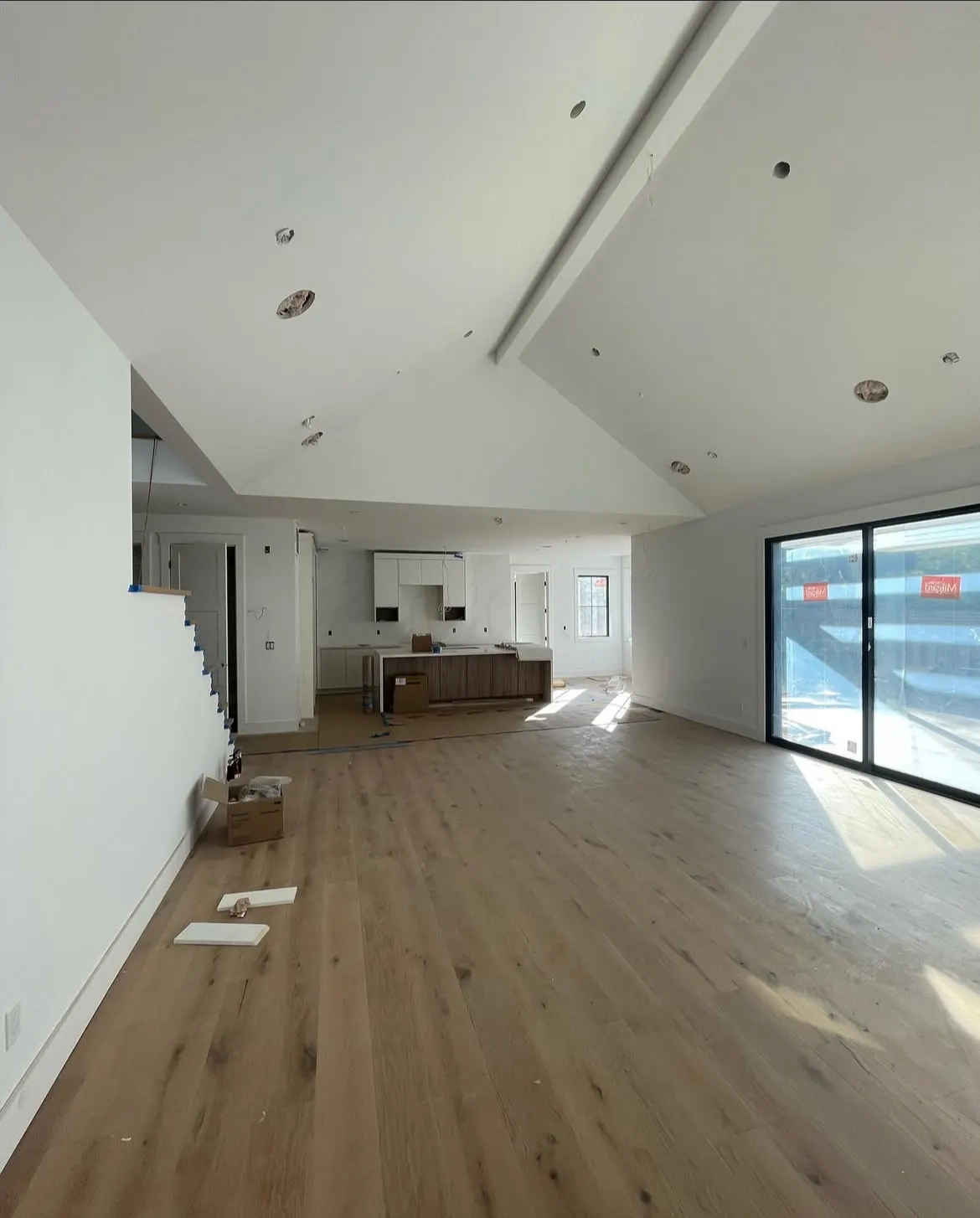 Open-plan living room with a vaulted white ceiling and oak floors